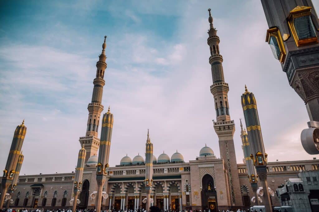 Exterior da mesquita Al-Masjid an-Nabawi em Medina, mostrando minaretes, cúpulas e um céu noturno que pode ser visitada com o eSIM Arábia Saudita.