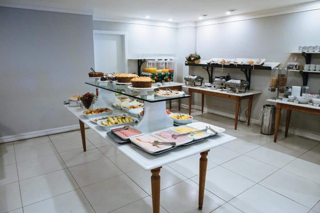 Área de café da manhã do Diamond Hotel no rio de janeiro, com frios, frutas, bolos à mostra na mesa em primeiro plano, além de sucos, bandejas com comidas quentes e outros quitutes ao fundo