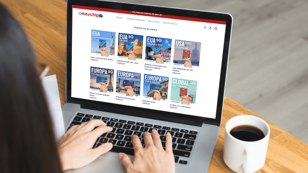 mulher digitando no computador em cima de uma mesa de madeira com uma xícara branca ao lado cheia de café. Na tela do computador é possível ver a página do site o meu chip